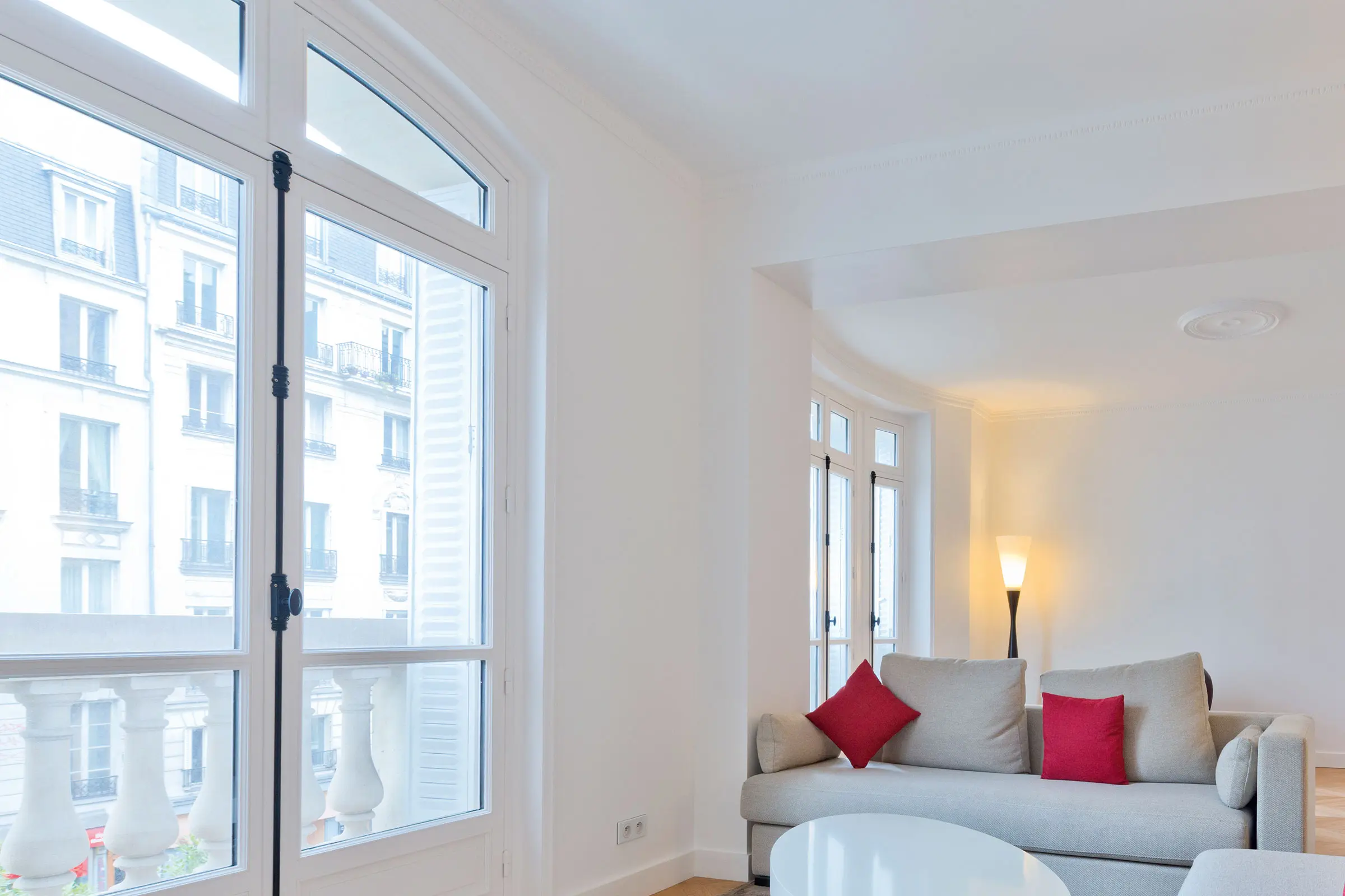 Wohnzimmer mit großer Fensterfront, weißen Wänden und hellen Möbeln