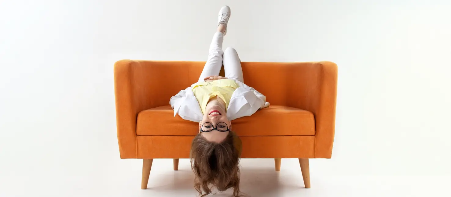 Lady lying upside down on an orange sofa